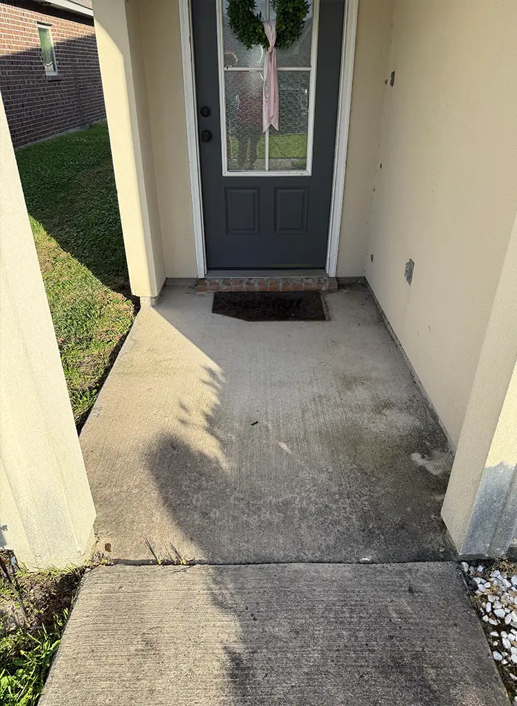 Front entryway before pressure washing, dingy concrete
